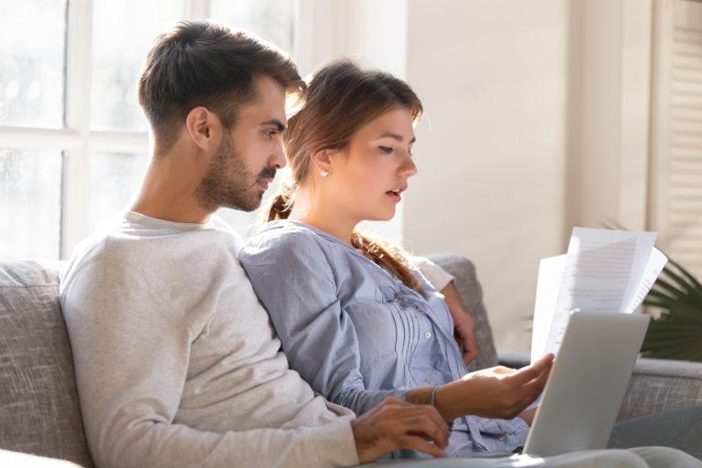 A man and a woman look at a laptop's screen.